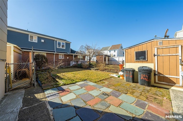 view of patio featuring an outbuilding, a gate, fence, a shed, and a residential view