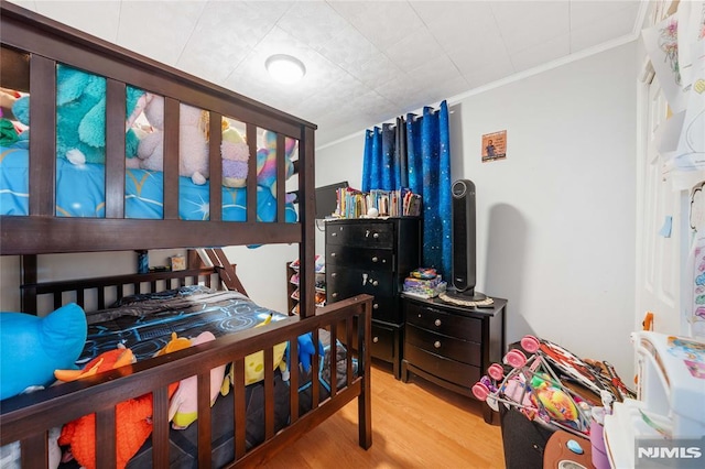 bedroom featuring crown molding and light wood finished floors