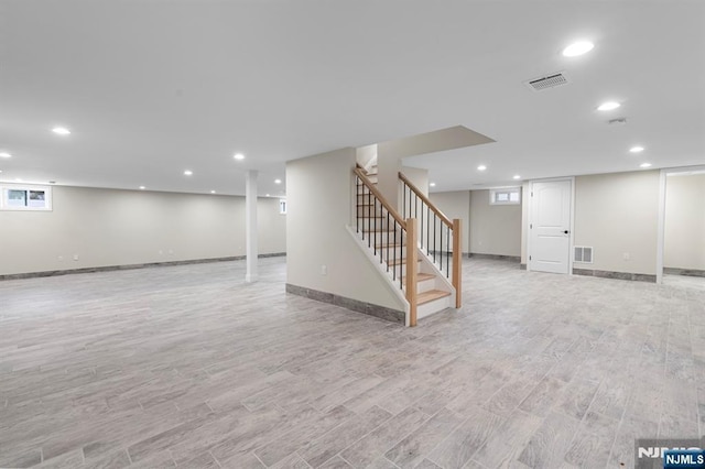 below grade area featuring light wood-style floors, recessed lighting, visible vents, and stairs