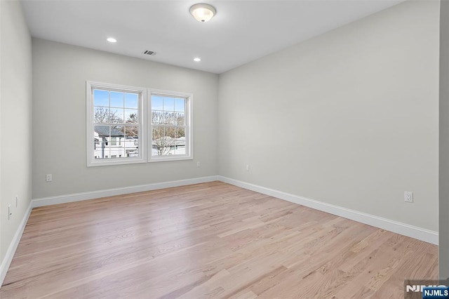 empty room with light wood-style flooring, visible vents, and baseboards