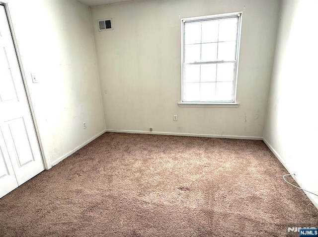 carpeted spare room with visible vents and baseboards