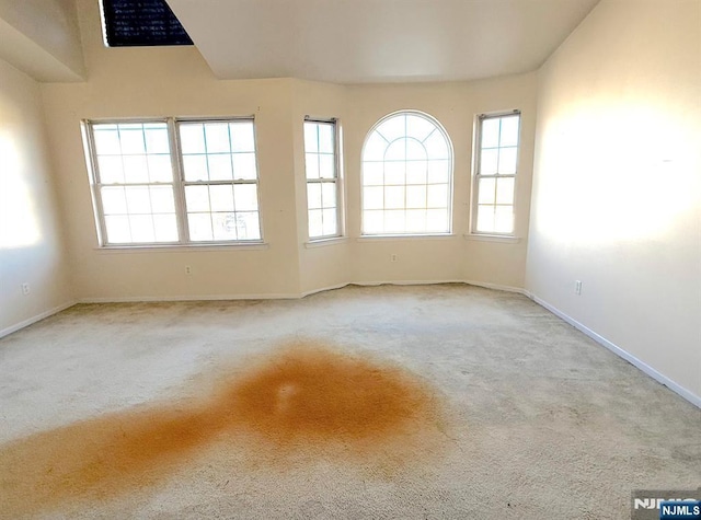 unfurnished room featuring light colored carpet and baseboards