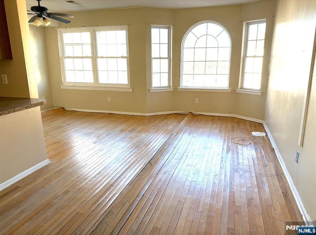 empty room with light wood-type flooring, visible vents, ceiling fan, and baseboards