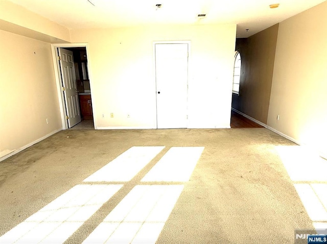 unfurnished bedroom featuring ensuite bath, baseboards, visible vents, and carpet flooring