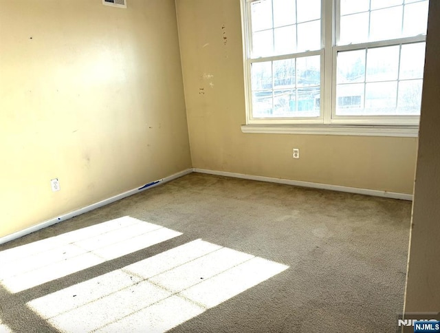 carpeted spare room with visible vents and baseboards