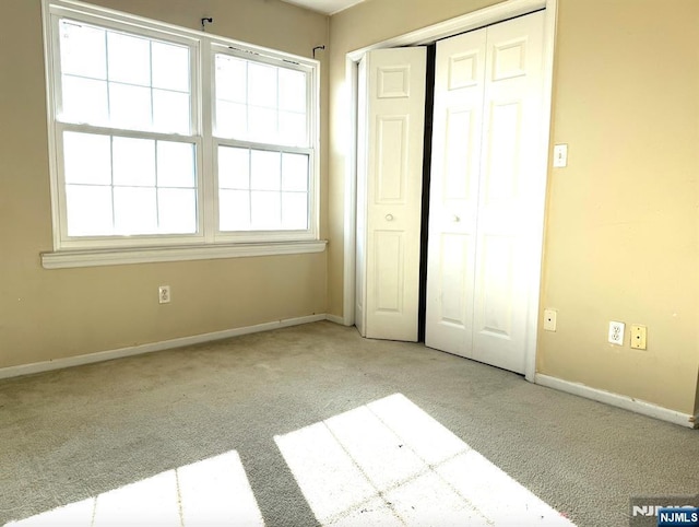 unfurnished bedroom with light carpet, baseboards, and a closet