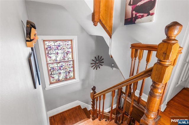 stairs featuring lofted ceiling, baseboards, and wood finished floors