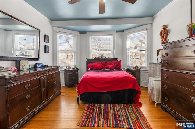 bedroom featuring light wood finished floors, ceiling fan, multiple windows, and ornamental molding