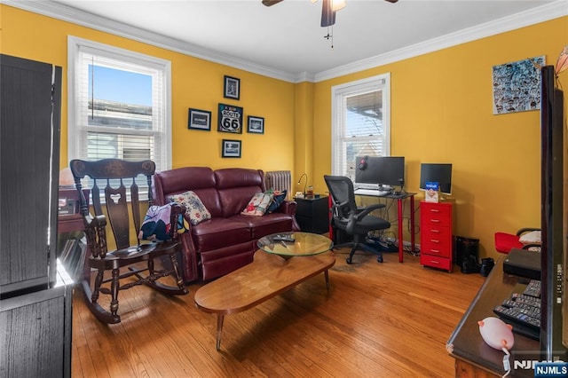 living area with a ceiling fan, ornamental molding, and wood finished floors