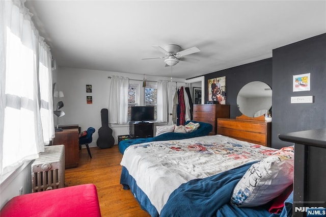 bedroom with radiator heating unit, a closet, a ceiling fan, and light wood-style floors