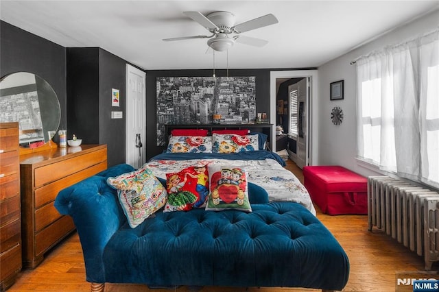 bedroom featuring light wood-style floors, radiator heating unit, and ceiling fan