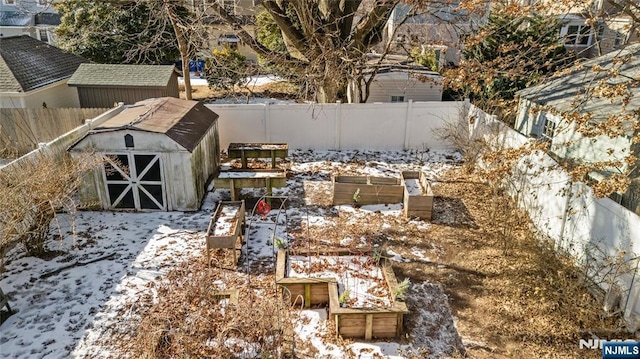 snowy yard featuring a fenced backyard, a storage unit, and an outbuilding