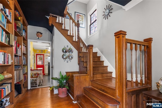 staircase featuring a towering ceiling and wood finished floors