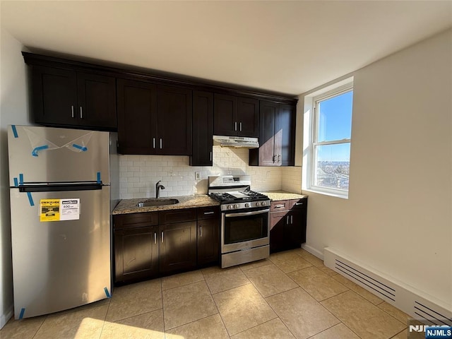 kitchen with appliances with stainless steel finishes, light stone countertops, under cabinet range hood, a baseboard heating unit, and a sink