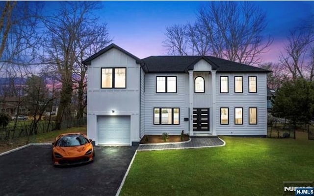 modern farmhouse style home featuring aphalt driveway, a yard, a garage, and fence