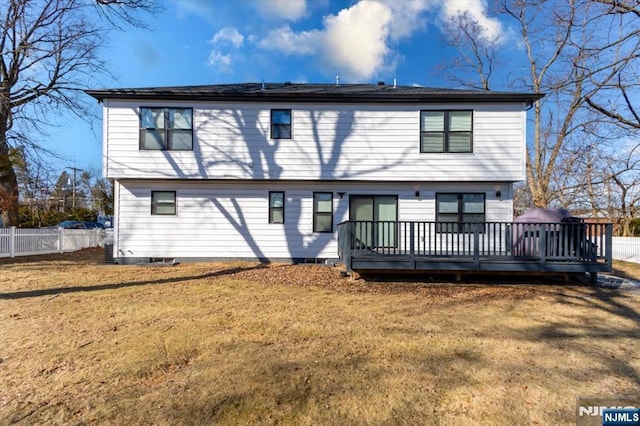 rear view of house with fence, a deck, and a yard