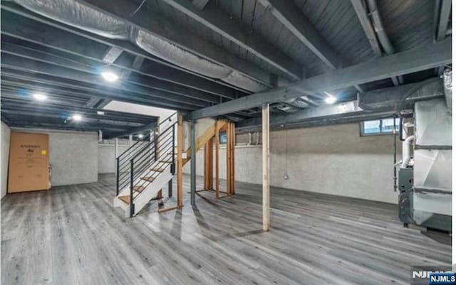 below grade area featuring heating unit, stairs, and wood finished floors