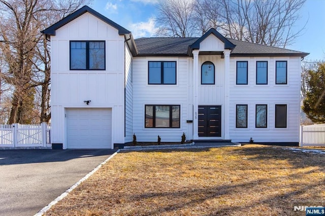 modern farmhouse featuring a garage, fence, aphalt driveway, and board and batten siding