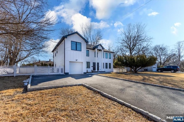 view of front of property featuring board and batten siding, fence, driveway, and a garage