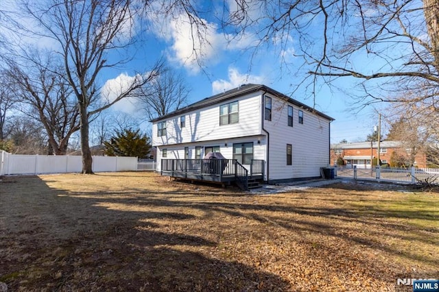 back of property with a fenced backyard, a yard, and a wooden deck