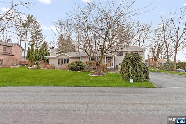 view of front of house with a front yard, a residential view, and a chimney