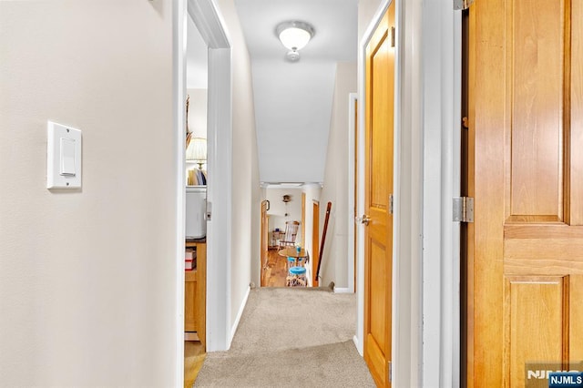 hallway featuring light carpet and baseboards