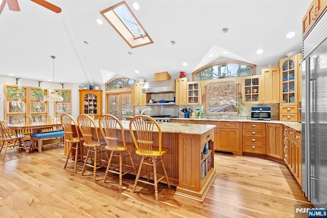 kitchen with high quality fridge, a breakfast bar, a center island, open shelves, and glass insert cabinets