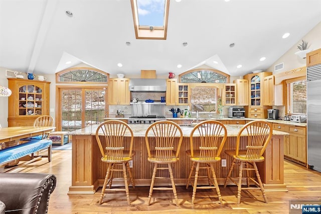 kitchen with plenty of natural light, lofted ceiling, glass insert cabinets, a breakfast bar, and a center island