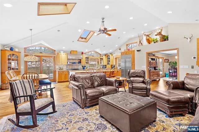 living room with high vaulted ceiling, light wood-style flooring, recessed lighting, a skylight, and a ceiling fan