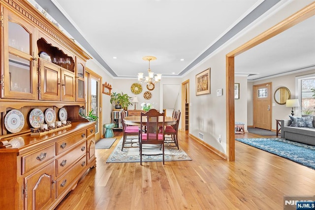 dining space featuring light wood finished floors, visible vents, a chandelier, and crown molding