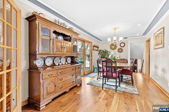 dining area featuring light wood-style floors, ornamental molding, french doors, and an inviting chandelier