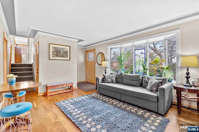 living area with stairs, baseboards, crown molding, and wood finished floors