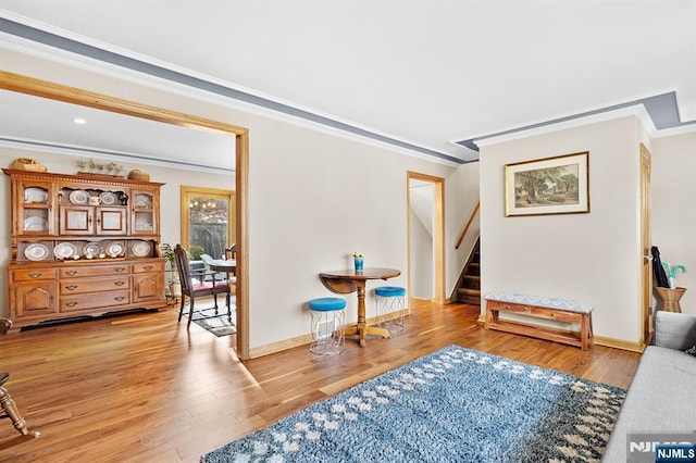 living room featuring ornamental molding, stairway, and light wood-type flooring