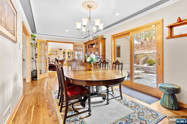 dining area featuring light wood-type flooring, visible vents, a chandelier, and french doors