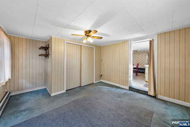 empty room with a baseboard heating unit, carpet floors, crown molding, and wallpapered walls