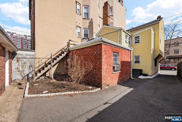 view of property exterior featuring stairs, brick siding, and stucco siding