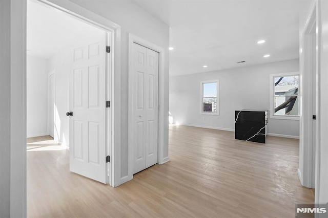 hall with light wood finished floors, baseboards, a wealth of natural light, and recessed lighting