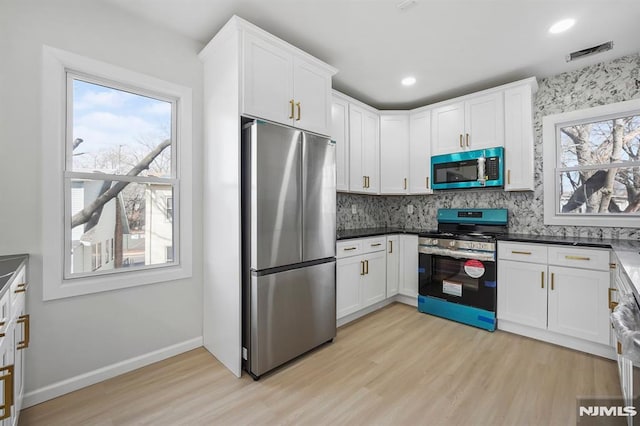 kitchen with dark countertops, white cabinetry, and appliances with stainless steel finishes