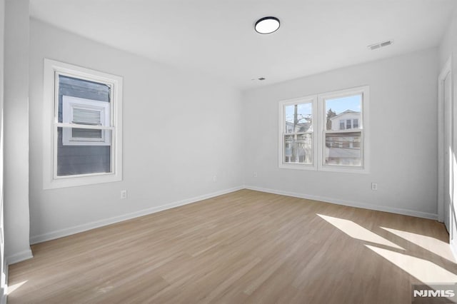 unfurnished room with baseboards, visible vents, and light wood-style floors