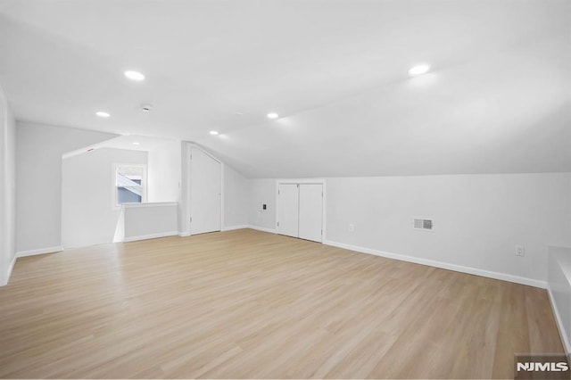 additional living space with lofted ceiling, visible vents, light wood-style flooring, and baseboards