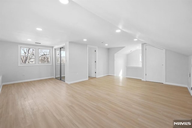 additional living space featuring light wood-style flooring, baseboards, and vaulted ceiling