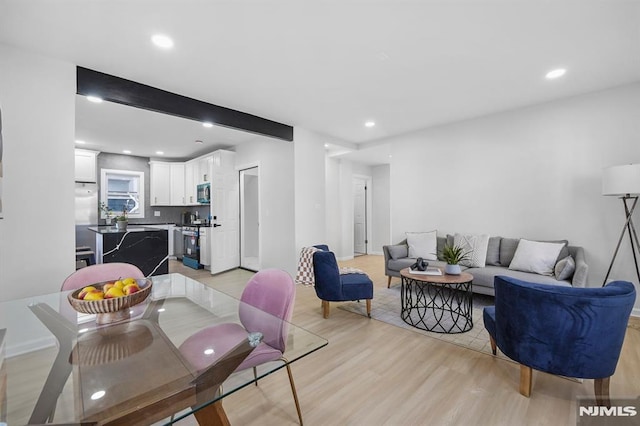 living area featuring light wood finished floors, beamed ceiling, and recessed lighting