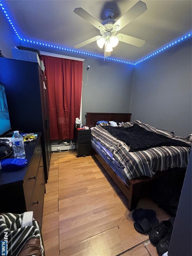 bedroom featuring light wood-style flooring and a baseboard heating unit