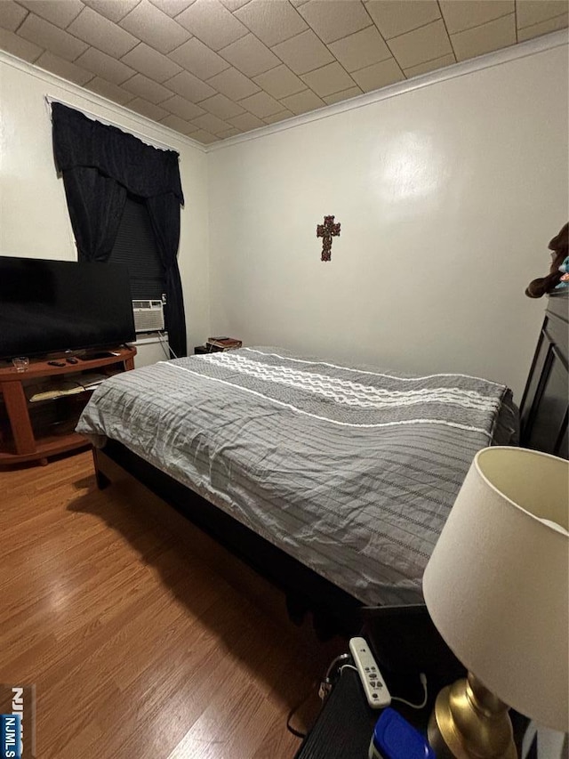 bedroom featuring ornamental molding and wood finished floors