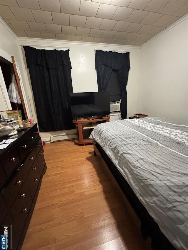 bedroom with light wood-style floors, cooling unit, ornamental molding, and baseboard heating