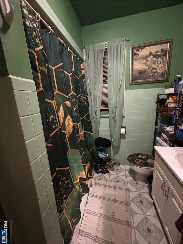 bathroom featuring tile walls, toilet, wainscoting, vanity, and tile patterned flooring