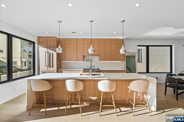 kitchen featuring pendant lighting, a spacious island, light countertops, light wood-style flooring, and modern cabinets