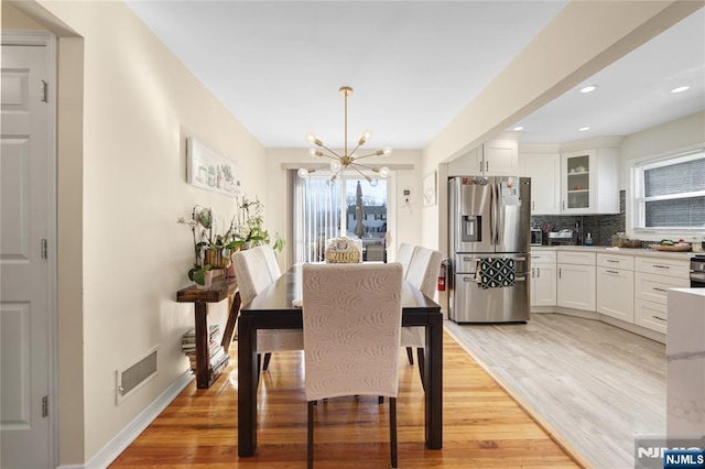 dining space featuring light wood finished floors, baseboards, visible vents, a chandelier, and recessed lighting