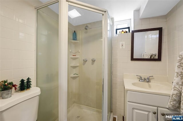 full bathroom with toilet, vanity, a shower stall, and tile walls