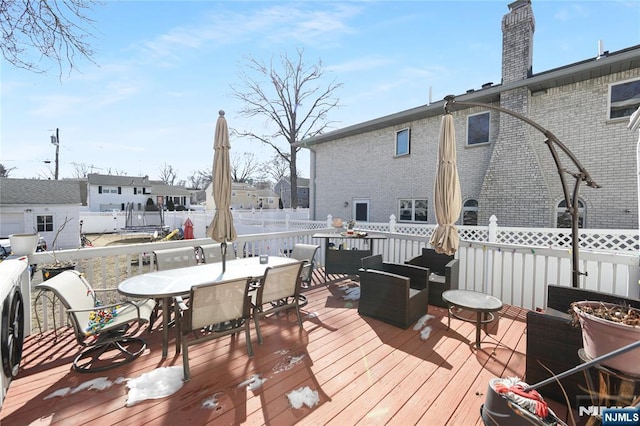 wooden terrace with outdoor dining space, outdoor lounge area, and fence